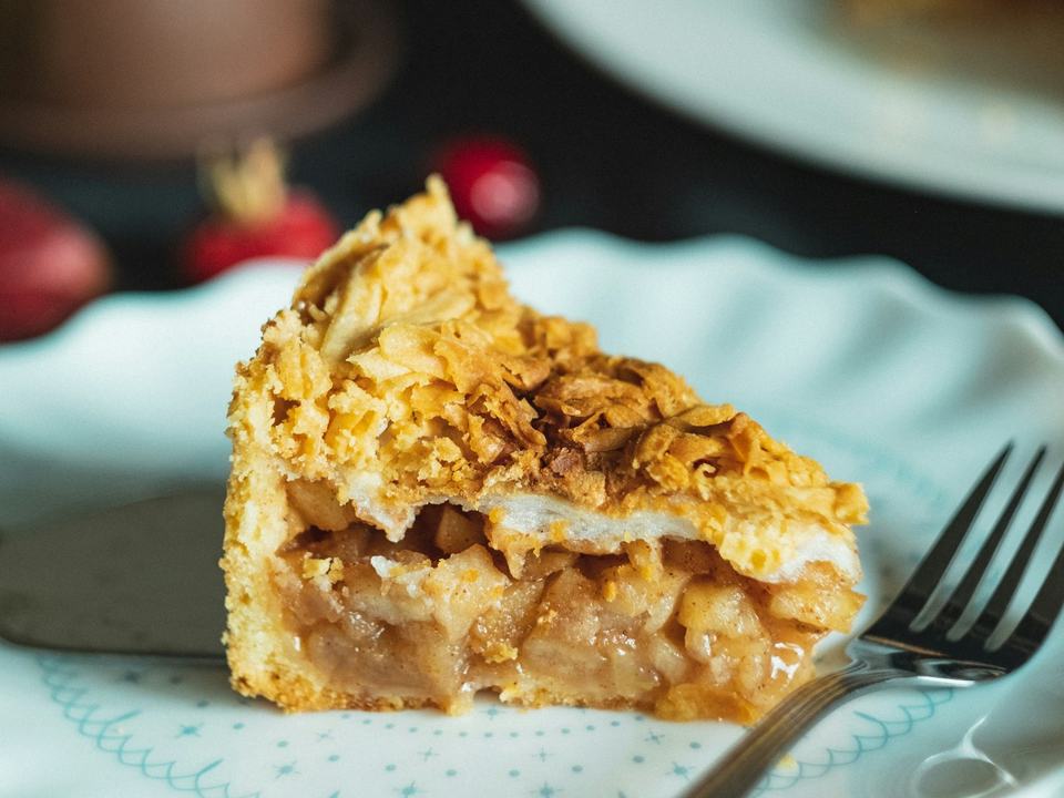 Een punt appeltaart met een gouden korst op een wit bordje