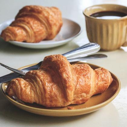 Twee croissants en een kop koffie op tafel